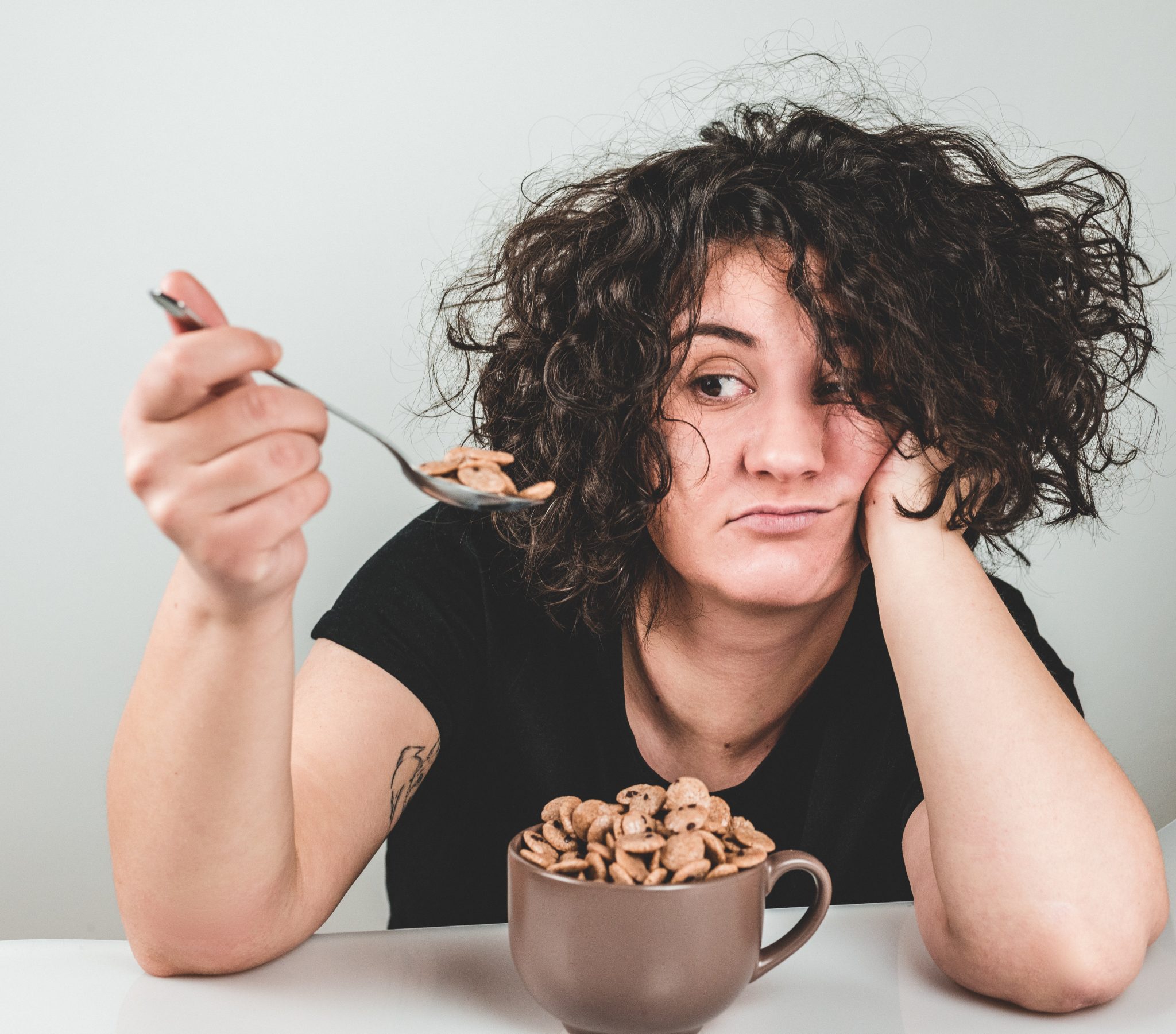 Lady eating cereal out of a mug looking unhappy