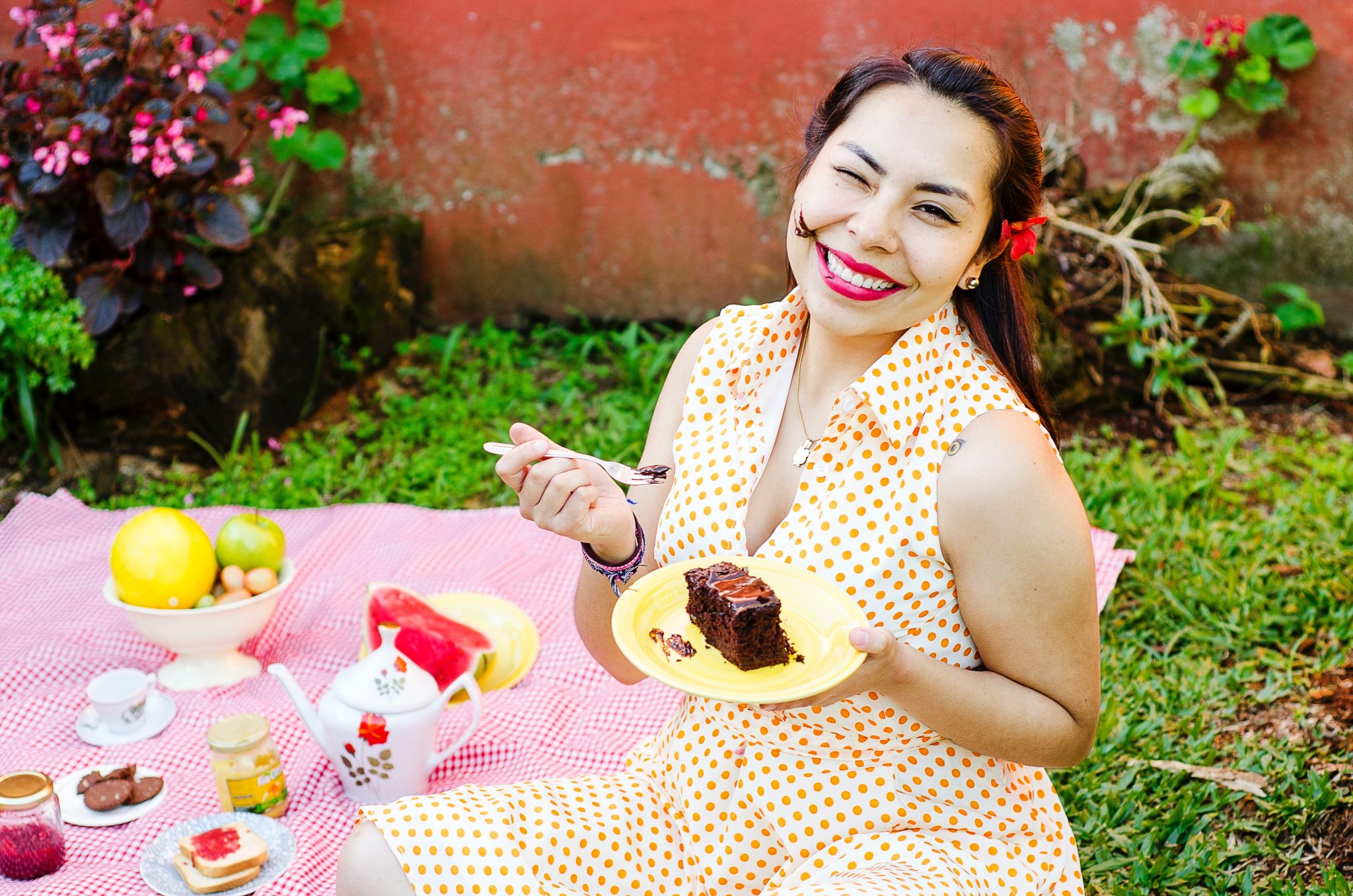 Lady eating cake on a picnic blanket smiling