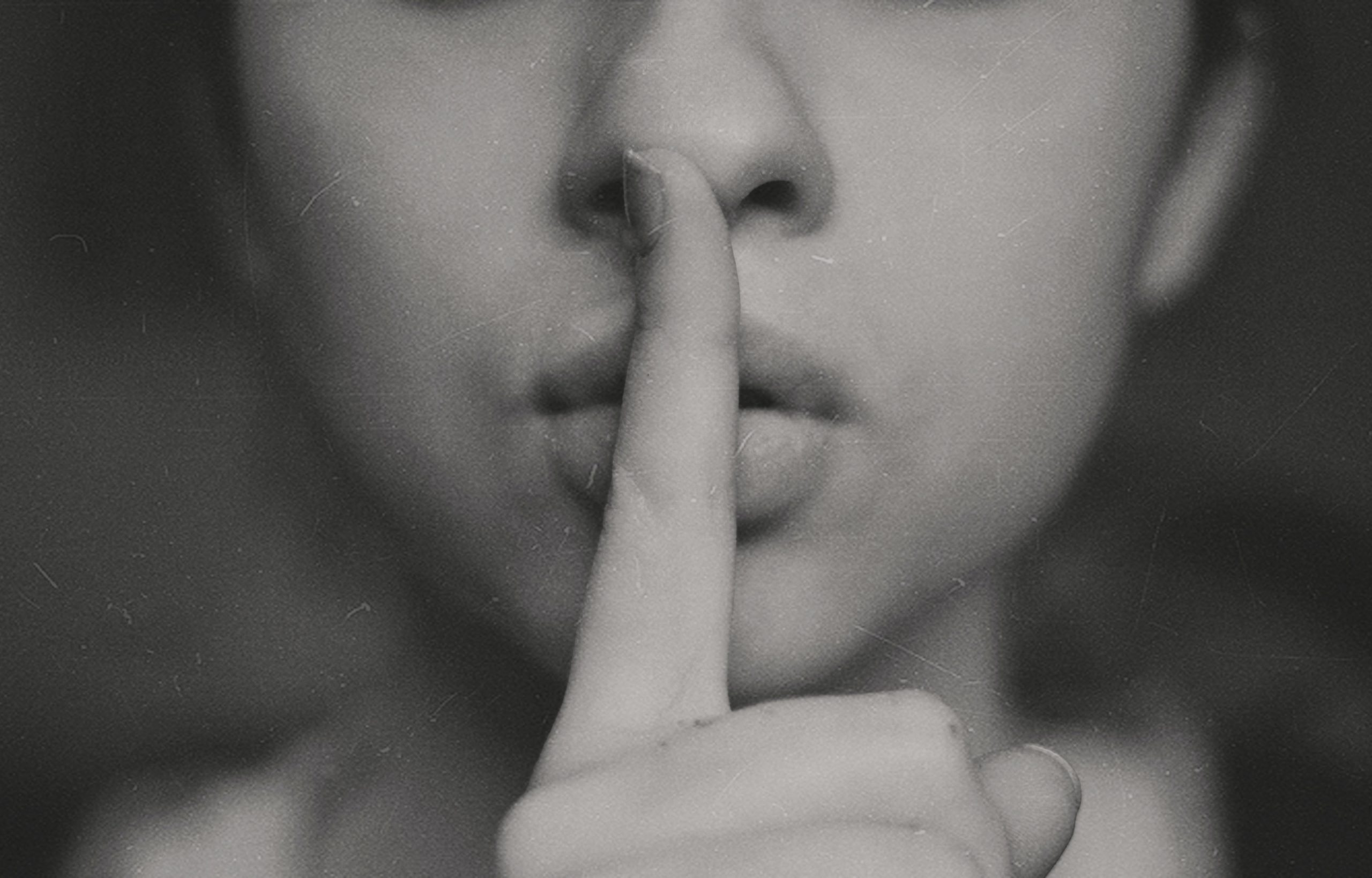 Woman holding finger to lips to suggest shhhh